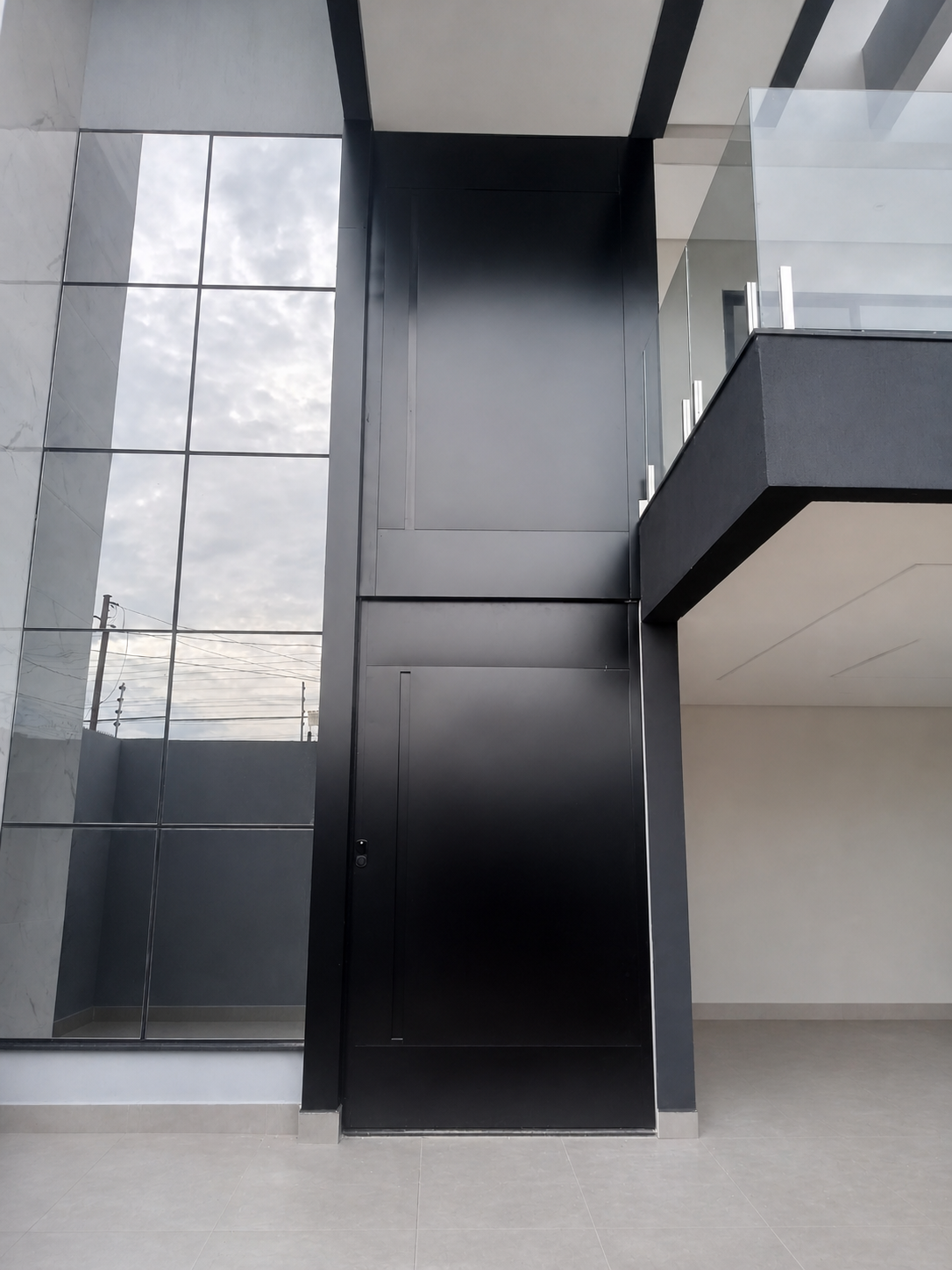 Porta alta preta NOAH instalada em fachada